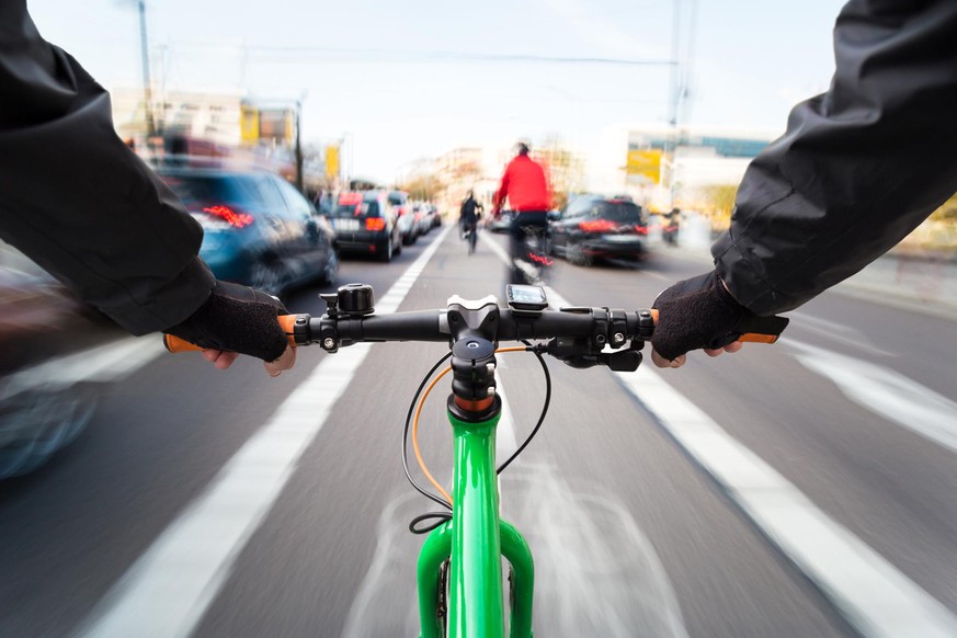 Cyclist drives on the bike path past the traffic jam - First-person view of cyclist/ motion blur