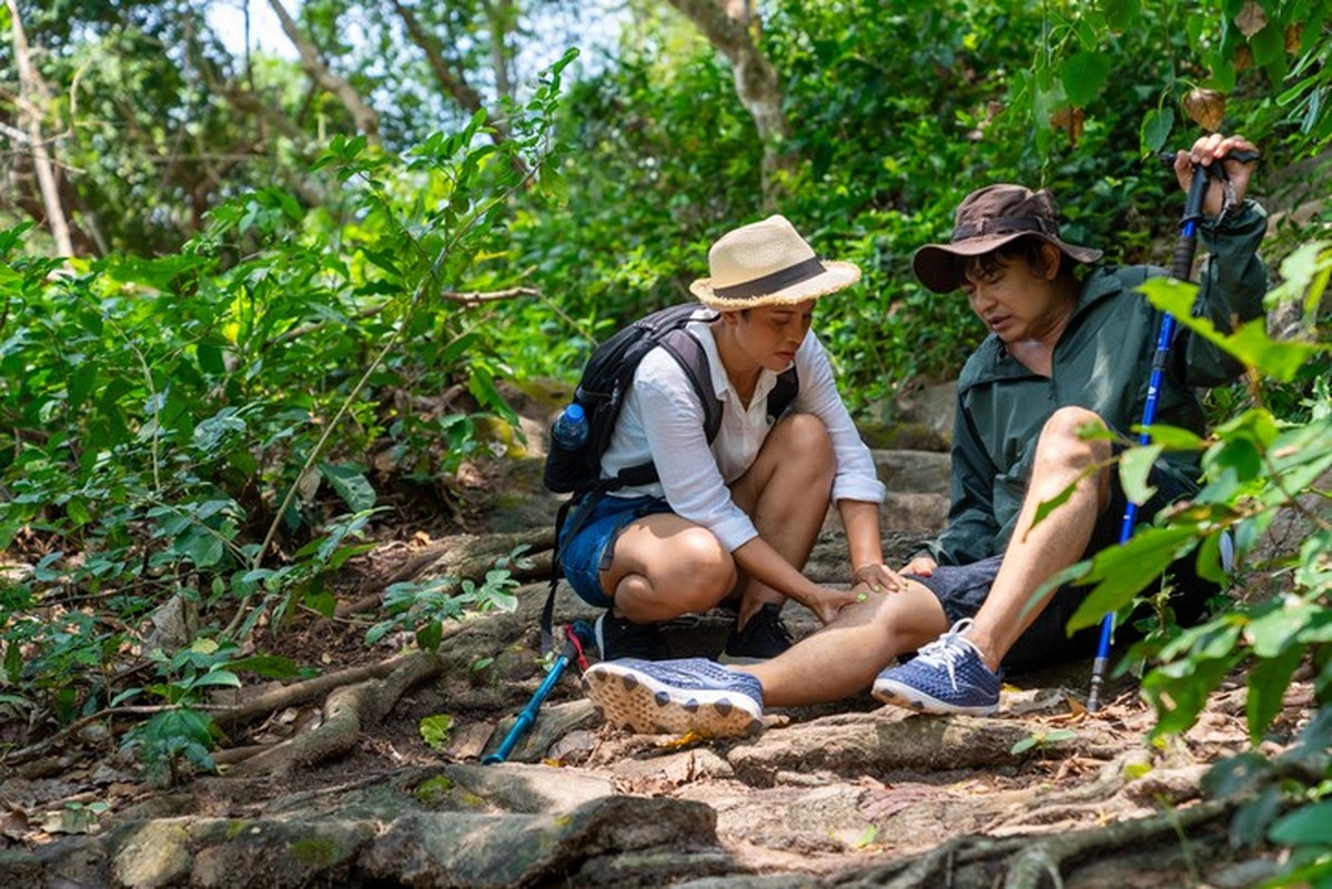 Asian family couple on summer holiday vacation. Mature adult couple hiking together in forest. Senior man injured on knee during trekking with his wife. Adventure travel and health care concept.