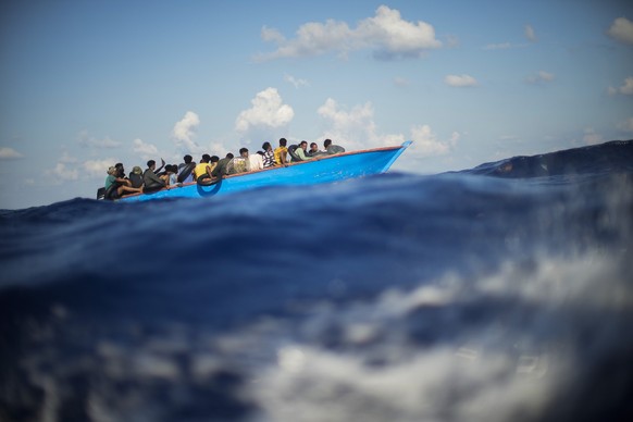 ARCHIV - 11.08.2022, Italien, ---: Migranten sitzen in einem Holzboot im Mittelmeer nahe der Insel Lampedusa. (zu dpa «Erneut Hunderte Bootsmigranten auf Lampedusa gelandet») Foto: Francisco Seco/AP/d ...