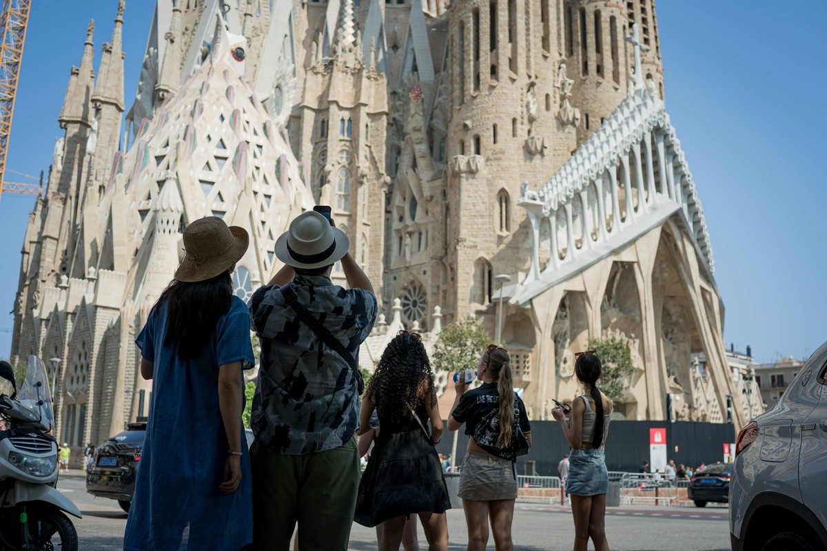 Tourism in Barcelona, Spain Barcelona, Spain - 21 August 2024: Tourists are seen taking pictures in front the Sagrada Familia church in the city center. With more than 18 million tourists expected to  ...