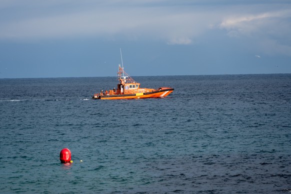 Orange rescue boat on a calm blue sea with a buoy in the foreground.