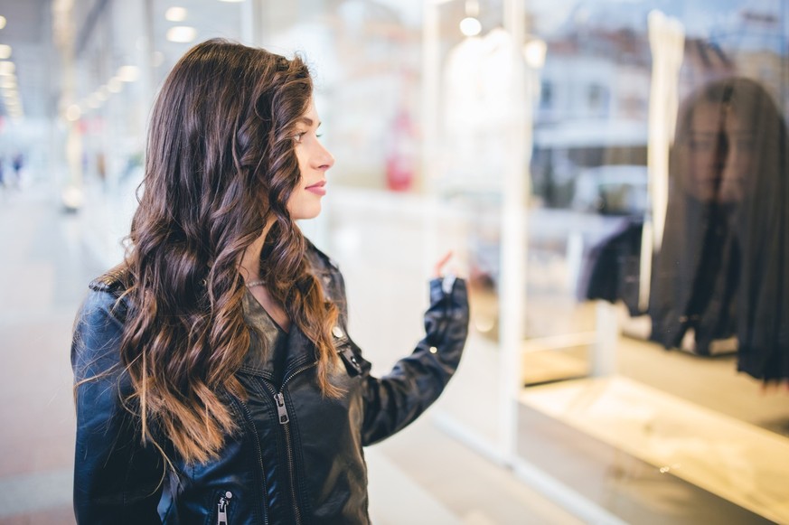 Beautiful and fashionable girl walking the city and looking at shop windows.