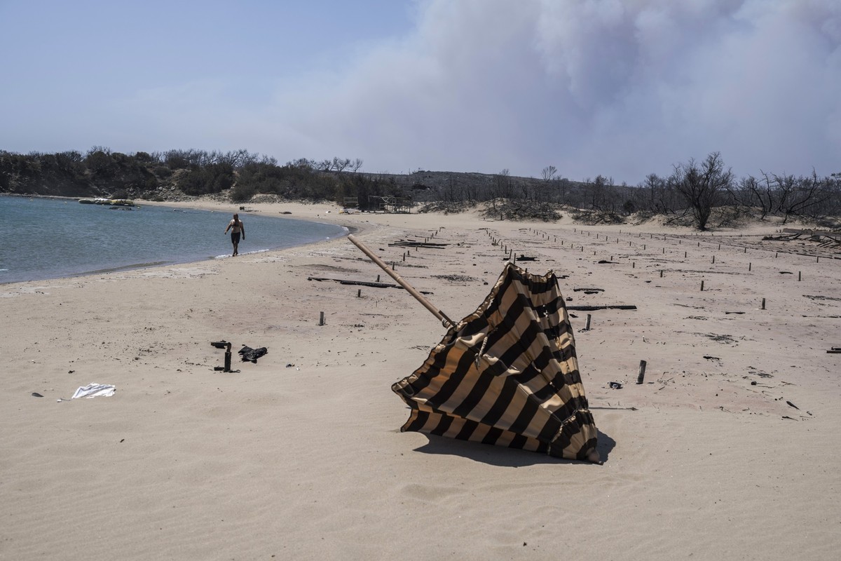 Ungewohnter Anblick: Zuvor ein Ort, an dem man sich gern aufhält, ist dieser Strand auf Rhodos nach einem Brand nahezu menschenleer. Im Hintergrund: verkohlte Sonnenliegen. Foto: Petros Giannakouris/A ...
