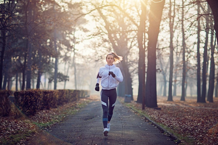 Young woman is running in the cold foggy morning