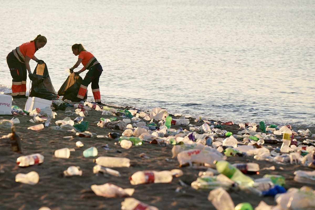 24.06.2024, Spanien, Malaga: Die Reinigungskräfte und Mitglieder der Nationalen Polizei sammeln am Strand von La Malagueta nach der Nacht von San Juan Müll ein. An den Stränden der spanischen Küste wi ...