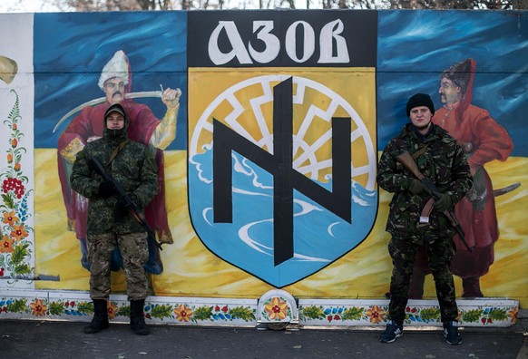 Kämpfer des Asow-Regiments posieren vor ihrer Flagge.