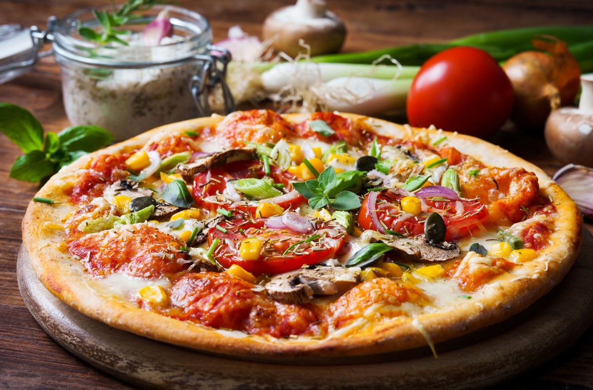 Homemade pizza with vegetables and fresh herbs