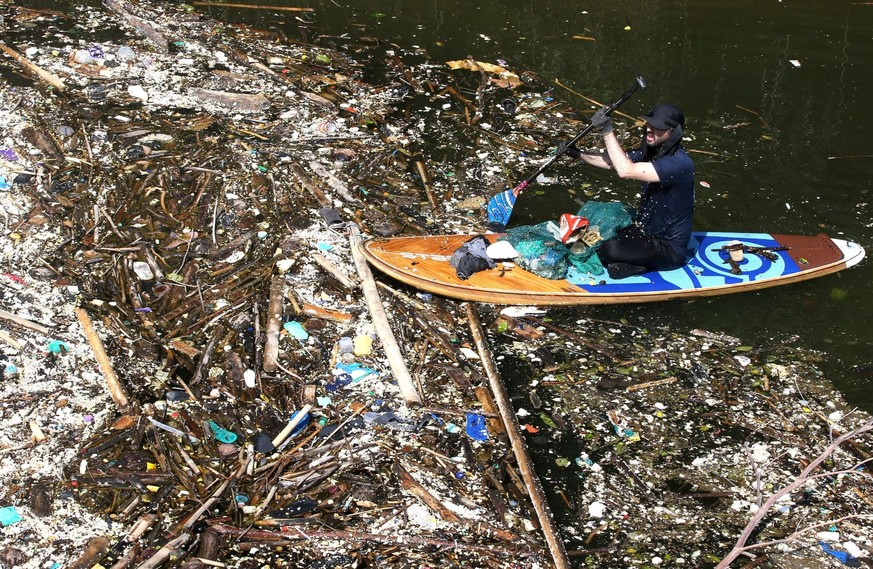 A volunteer sitting on a paddle board, picks up trash on a river at Pecatu, Bali, Indonesia on Friday, March 22, 2024. During monsoon season some rivers are being strewn by plastic rubbish and debris. ...
