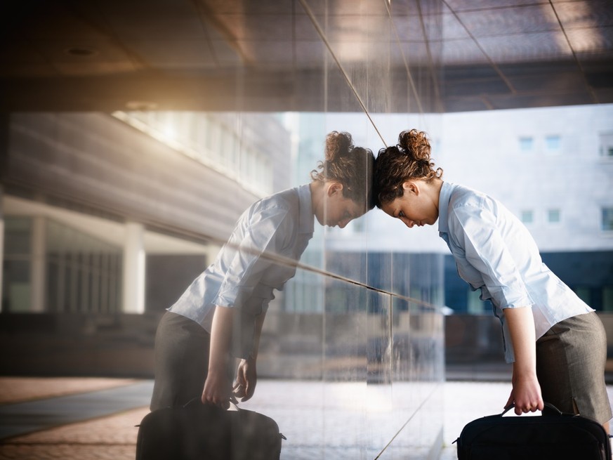 mid adult italian woman banging her head against a wall outside office building. Horizontal shape, copy space