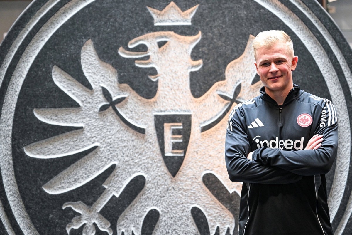 Jonathan Burkardt Eintracht Frankfurt posiert f�r ein Foto vor dem Eintracht-Vereinswappen, Eintracht Frankfurt stellt Neuzugang Jonathan Burkardt in einer Pressekonferenz vor, 07.07.2025. Pressekonfe ...