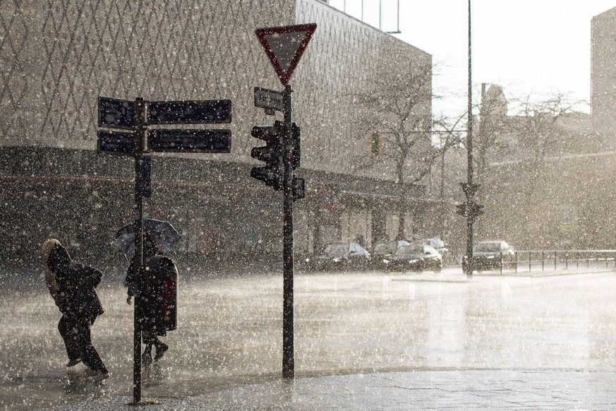 Regenschauer über Charlottenburg in der Kantstraße, Viele tausend Wassertropfen schimmern golden durch die untergehende Sonne, während eines kräftigen Regenschauers in der Kantstraße in Berlin-Charlot ...