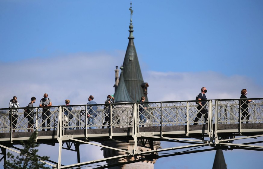 ARCHIV - 03.09.2020, Bayern, Schwangau: Touristen stehen auf der Marienbrücke vor Schloss Neuschwanstein. In der Nähe des Schlosses Neuschwanstein hat ein Mann zwei Frauen angegriffen und verletzt. Ei ...
