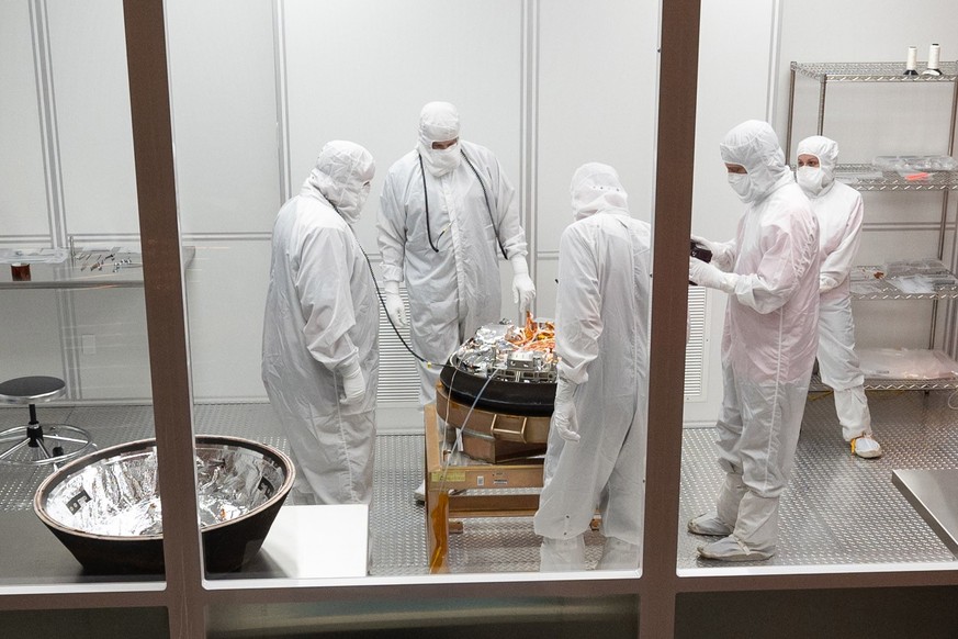 HANDOUT - 24.09.2023, USA, Dugway: Wissenschaftler arbeiten an der von der Nasa-Sonde «Osiris-Rex» über der Erde abgeworfenen Kapsel mit einer Geröllprobe vom Asteroiden Bennu in einem Reinraum auf de ...