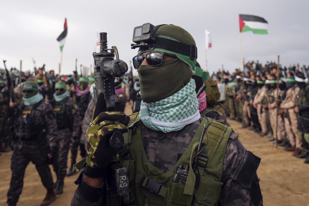 20.02.2025, Palästinensische Gebiete, Chan Junis: Vermummte und bewaffnete Kämpfer der Terrororganisation Hamas gehen in Stellung, bevor sie die Leichen von vier israelischen Geiseln, darunter eine Mu ...