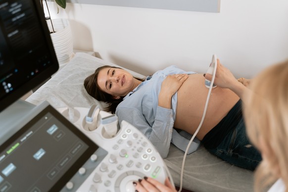 Eine schwangere Frau wird bei der Gynäkologin mit Ultraschall untersucht.
