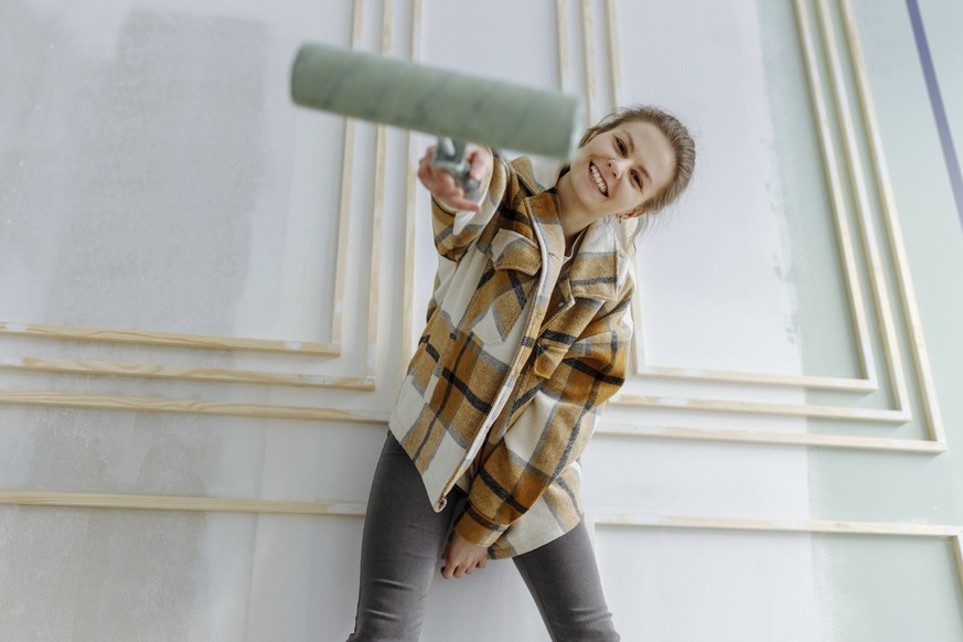 Smiling woman with paint roller in front of wall at home model released, Symbolfoto property released, VIVF00162