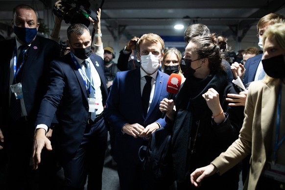Journalists gather around French President Emmanuel Macron as he arrives for the COP26 UN Climate Summit in Glasgow on November 1, 2021. More than 120 world leaders meet in Glasgow in a &quot;last, be ...