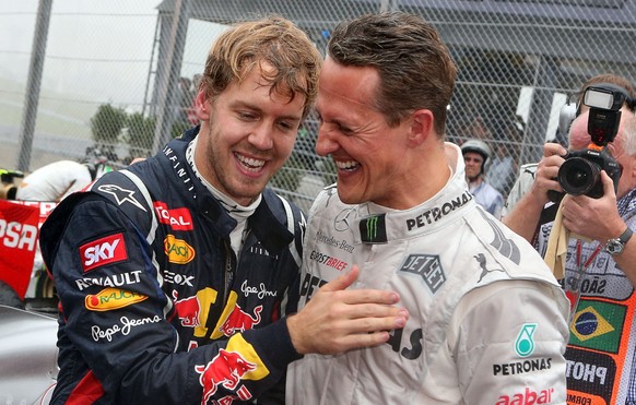 ARCHIV - 25.11.2012, Brasilien, S�o Paulo: Der deutsche Formel-1-Fahrer Sebastian Vettel (l) feiert mit Michael Schumacher im Autodromo Jose Carlos Pace seinen dritten Weltmeistertitel in Folge. Sebas ...