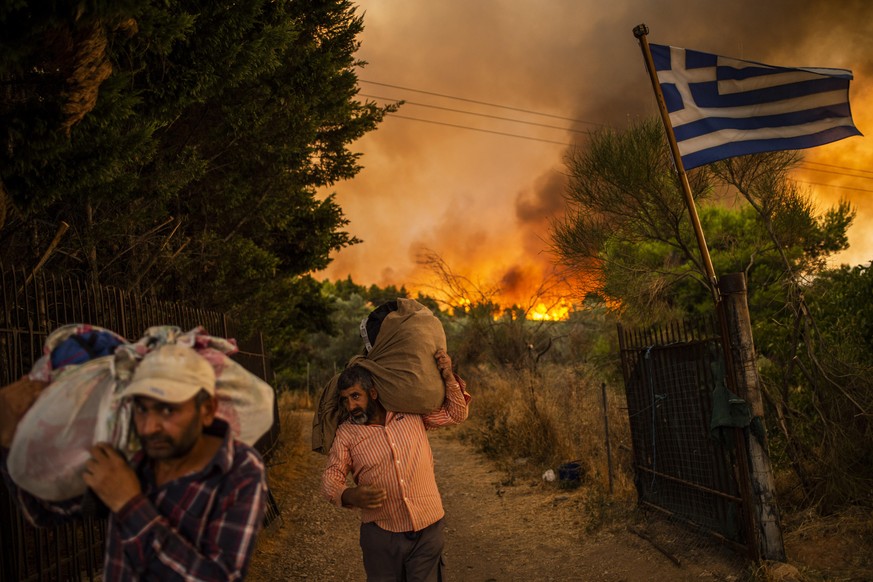 Menschen versuchen Teile ihrer Habe in Sicherheit zu bringen, während ein Waldbrand in einem Waldgebiet nördlich von Athen wütet. Das Feuer nördlich von Athen ist am Donnerstagabend erneut voll aufgef ...