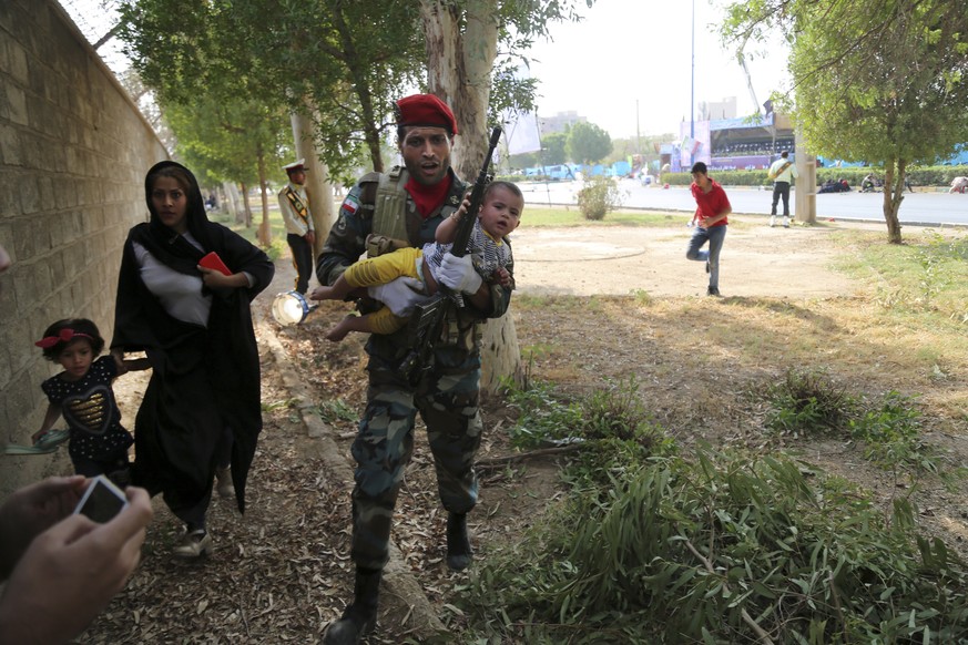 In this photo provided by Mehr News Agency, an Iranian army member carries away a child from a shooting scene during a military parade marking the 38th anniversary of Iraq&#039;s 1980 invasion of Iran ...
