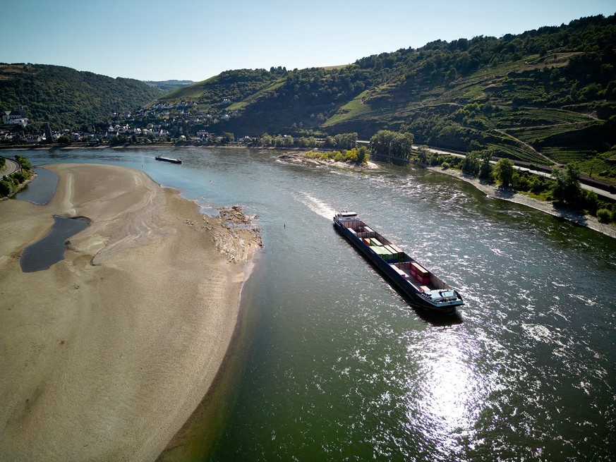 ARCHIV - 19.07.2022, Rheinland-Pfalz, Oberwesel: Ein Frachtschiff passiert im Juli 2022 auf dem Rhein eine Sandbank (Luftaufnahme mit einer Drohne). Trotz lang anhaltender Sommerhitze und extremen Nie ...