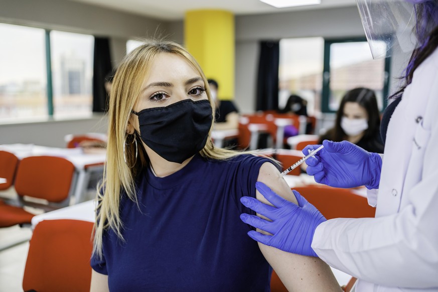 Nurse gives students a vaccination in school during coronavirus pandemic