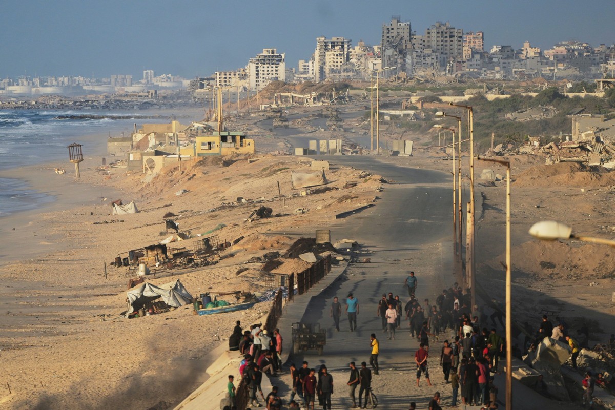 Israeli tanks are positioned on the coastal road leading to Gaza City as displaced Palestinians gather near Wadi Gaza in the central Gaza Strip, Thursday, Oct. 9, 2025. (AP Photo/Abdel Kareem Hana)