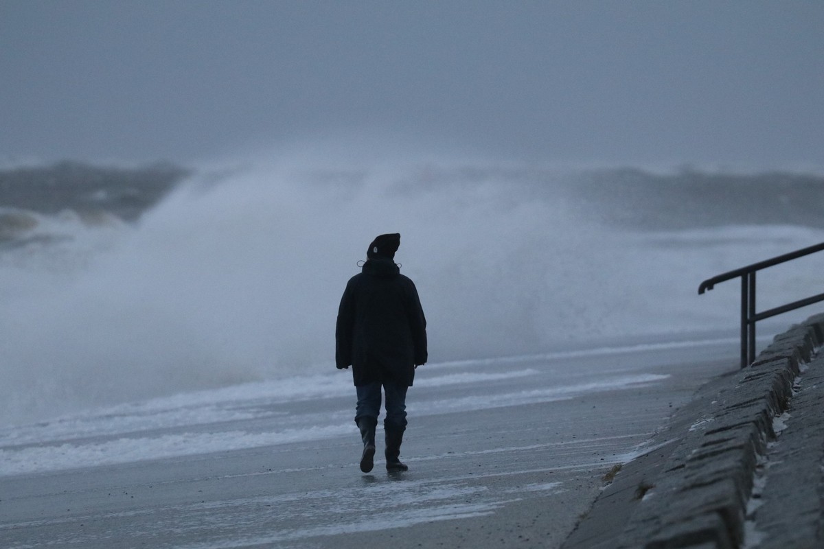 24.11.2023, Niedersachsen, Norderney: Eine Spazierg�ngerin l�uft bei st�rmischem Wetter am Nordstrand der ostfriesischen Insel Norderney. In Hamburg und an der Nordseek�ste hat eine Sturmflut in der N ...