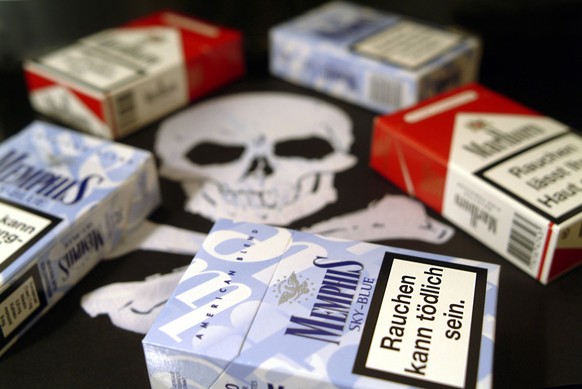 Rauchen kann tödlich sein- Zigarettenschachteln liegen auf einem Totenkopf.