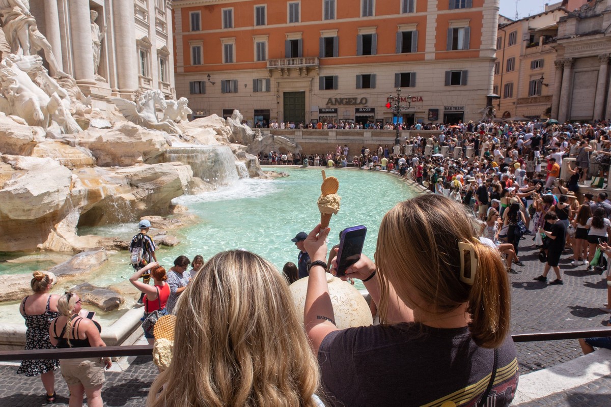 Italy: Tourists in Rome on a hot summer day A woman takes a selfie with an ice cream in front of Trevi Fountain in Rome, on a hot summer day Rome Italy Copyright: MatteoxNardone