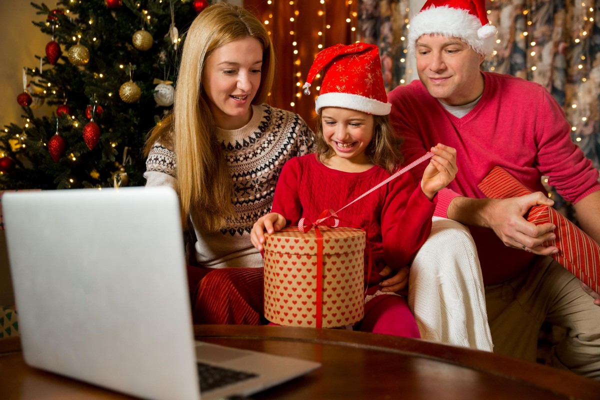 A happy couple with a child is celebrating Christmas with their friends on video call using webcam. Family greeting their relatives on Christmas eve online. New normal