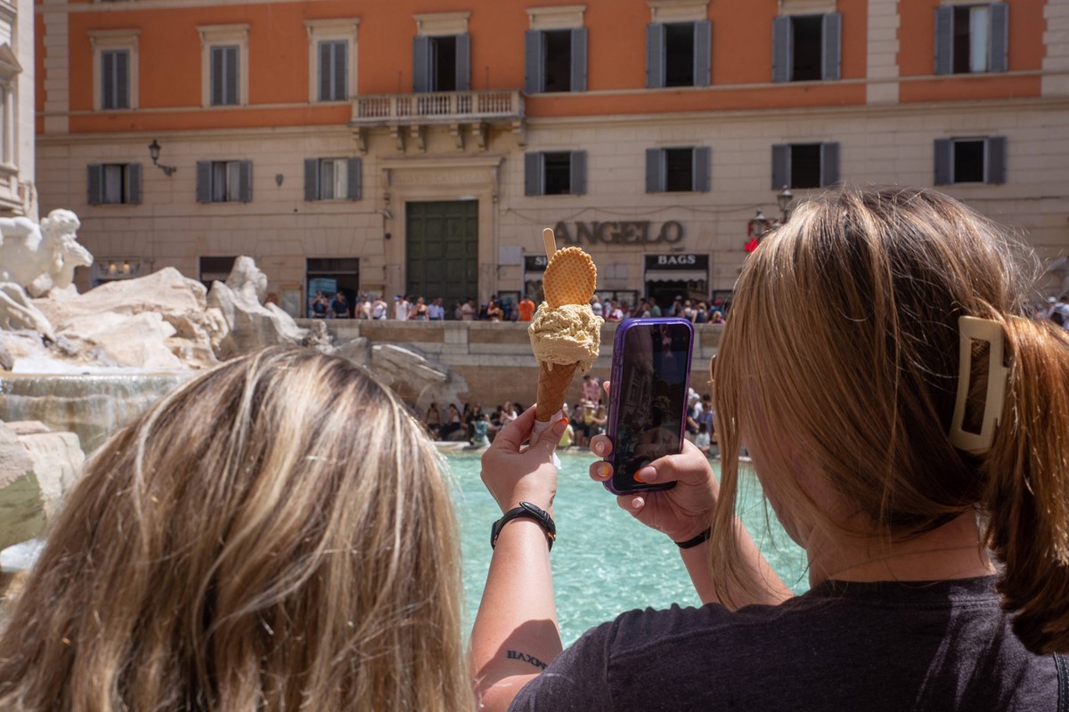 Italy: Tourists in Rome on a hot summer day A woman takes a selfie with an ice cream in front of Trevi Fountain in Rome, on a hot summer day Rome Italy Copyright: MatteoxNardone