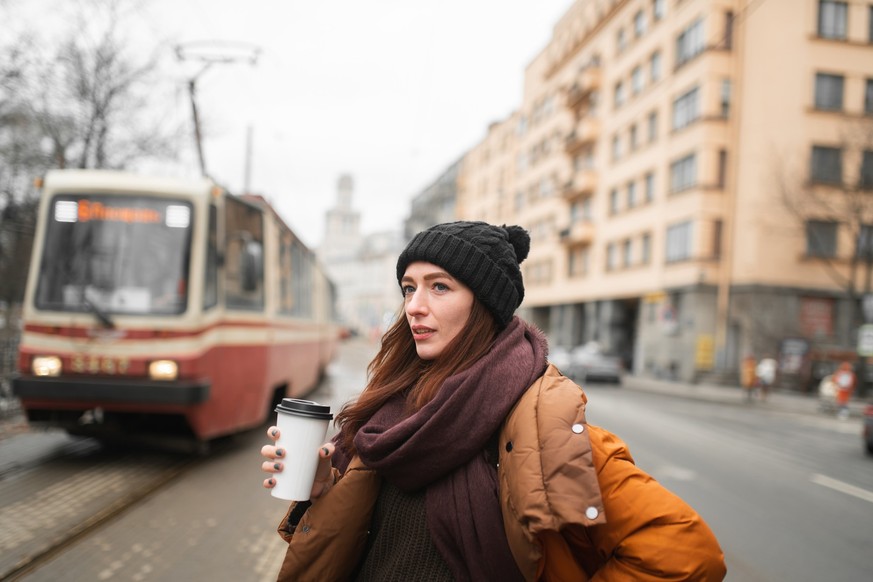 Young woman with glass of coffee in hand is late for work.