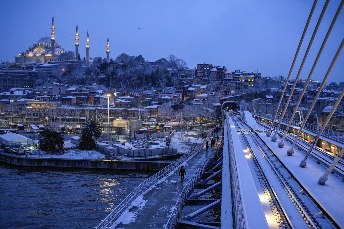 Backdropped by the historical Suleymaniye mosque, people walk on the Golden Horn Bridge after a snowfall in Istanbul, Turkey, Friday, Feb. 21, 2025. (AP Photo/Emrah Gurel)