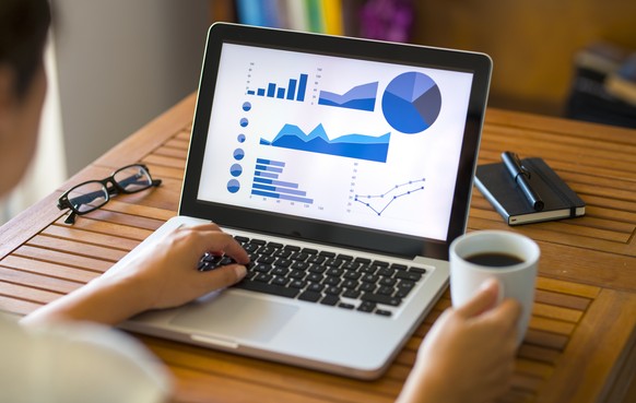 Woman using laptop computer displaying financial charts.