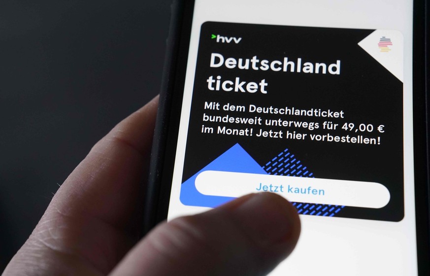 ILLUSTRATION - 03.04.2023, Hamburg: Ein Mann tippt auf seinem Smartphone zum Kauf des Deutschlandtickets auf die HVV-Switch-App. Rund sieben Millionen Menschen haben nach Angaben des Verbands deutsche ...