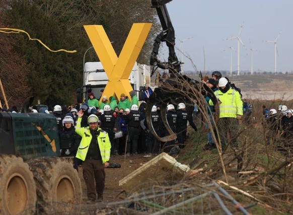 10.01.2023, Nordrhein-Westfalen, Erkelenz: Polizisten stehen am Rand der Ortschaft Lützerath Klimaschutzaktivisten gegenüber. Lützerath soll zur Erweiterung des Braunkohletagebaus Garzweiler II abgeba ...