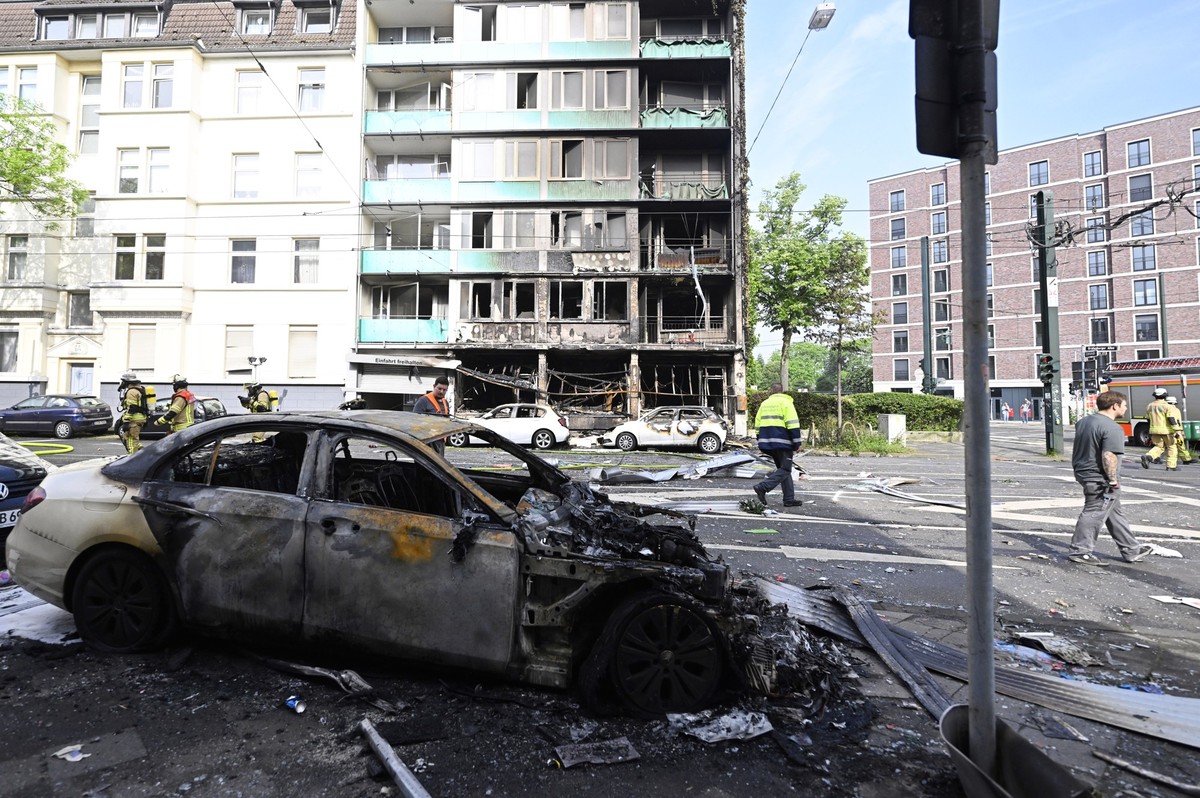 16.05.2024, Nordrhein-Westfalen, Düsseldorf: Ein ausgebranntes Auto steht vor einem Wohnhaus, in dem ein Brand wütete. Bei dem Brand in Düsseldorf sind mehrere Menschen ums Leben gekommen und weitere  ...