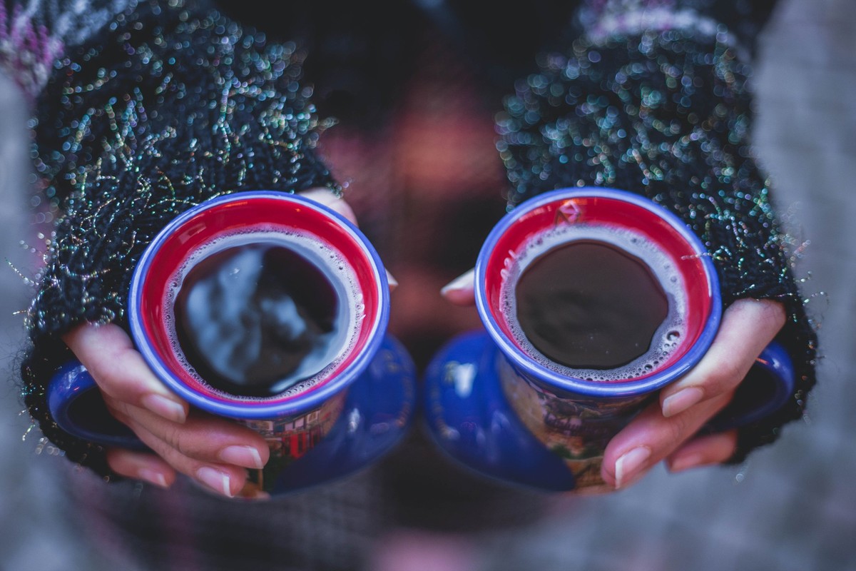 Close up on woman&#039;s hans holding two cup of mulled red wine. Females hands holding hot drinks, while wearing fingerless gloves and winter coat. Christmas market concept.