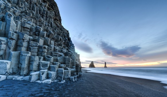 Wide view of Reynisdrangar rock formations on Reynisfjara Beach at sunrise, Halsanefhellir, Iceland.