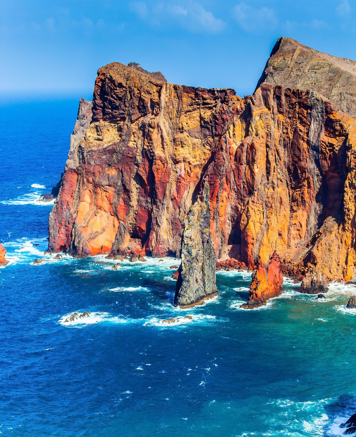 Madeira is a magical island in the Atlantic. The west coast of the island - red rocks, azure surf. The blinding midday sun illuminates the rocky shore. The concept of active, ecological and photo tour ...