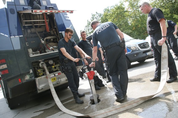 Polizisten füllen Tanks eines Wasserwerfers, um die Feuerwehr zu unterstützen.