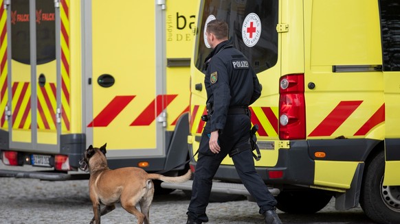 24.10.2023, Pulsnitz: Ein Polizist läuft nach einer eingegangen Drohung mit einem Hund vor einer Grund- und Oberschule im ostsächsischen Pulsnitz. Auch andere Schulen in Sachsen waren betroffen. Die S ...