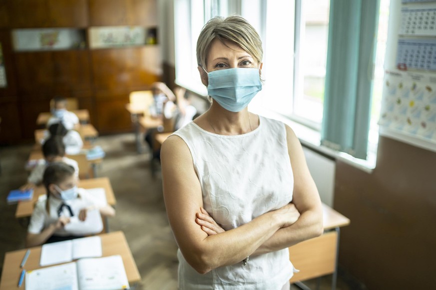 Young elementary teacher wearing a protective face mask at school.