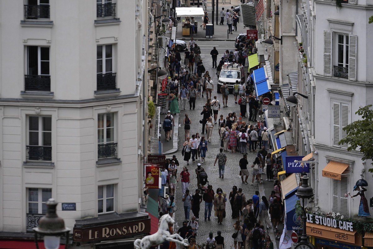 Parisians and tourists mix on a street near the Sacre Coeur of Montmartre Basilica, ahead of the 2024 Summer Olympics, Monday, July 22, 2024, in Paris, France. (AP Photo/Rebecca Blackwell)