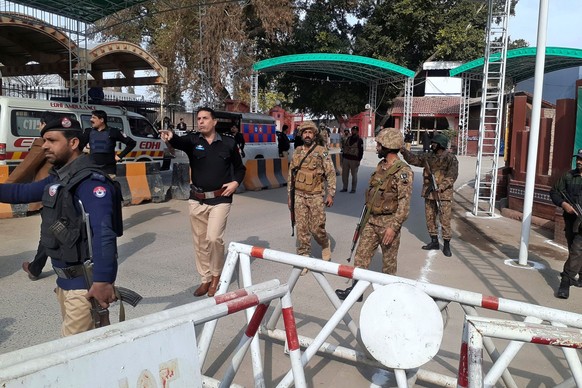Army soldiers and police officers clear the way for ambulances rushing toward a bomb explosion site, at the main entry gate of police offices, in Peshawar, Pakistan, Monday, Jan. 30, 2023. A powerful  ...