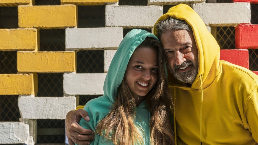 Smiling father and daughter standing against brick wall model released Symbolfoto DLTSF01124