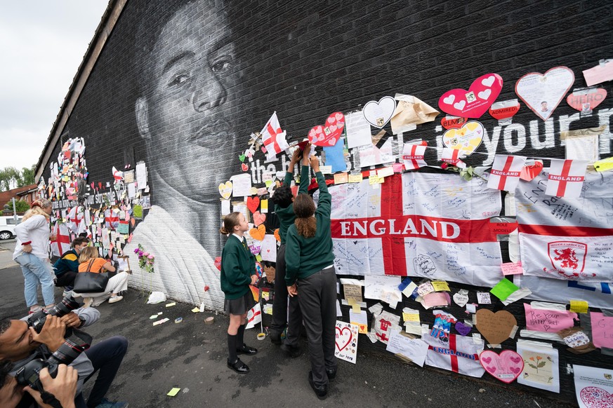 Euro 2020. Children from Kentigern&#039;s Primary School, (left to right) Millie, Austin and Ramah next to mural of Manchester United striker and England player Marcus Rashford on the wall of the Coff ...