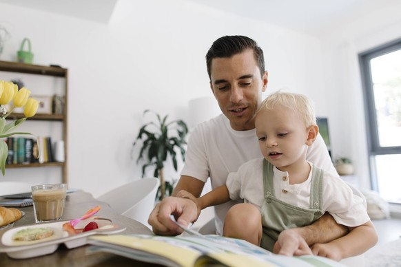 Father and son sitting with book at table model released, Symbolfoto property released, TYF00254