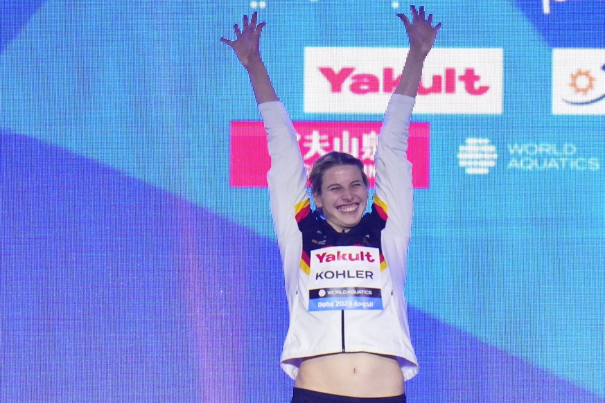 12.02.2024, Katar, Doha: Schwimmen: Weltmeisterschaft, 100 m Schmetterling, Frauen, Finale: Angelina Köhler aus Deutschland jubelt auf dem Podium über ihren Sieg. Foto: Hassan Ammar/AP/dpa +++ dpa-Bil ...